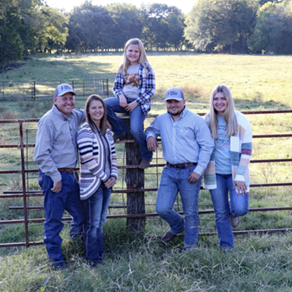 Salmon Enterprises Salmon Enterprises' family standing in front of a fenced pasture