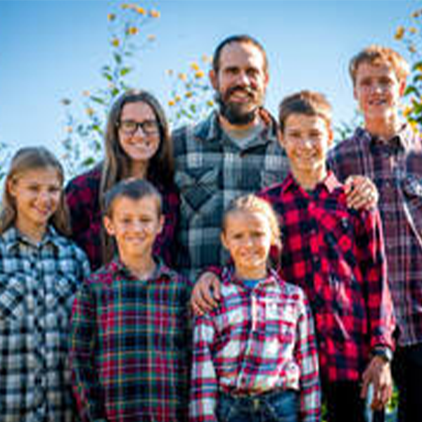A family of seven poses together in plaid shirts A family of seven poses together in plaid shirts