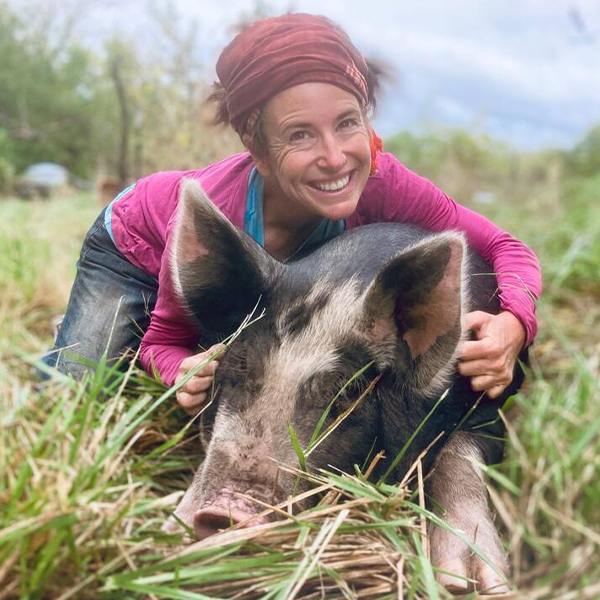 A farmer smiling and posing with a spotted pig A farmer smiling and posing with a spotted pig
